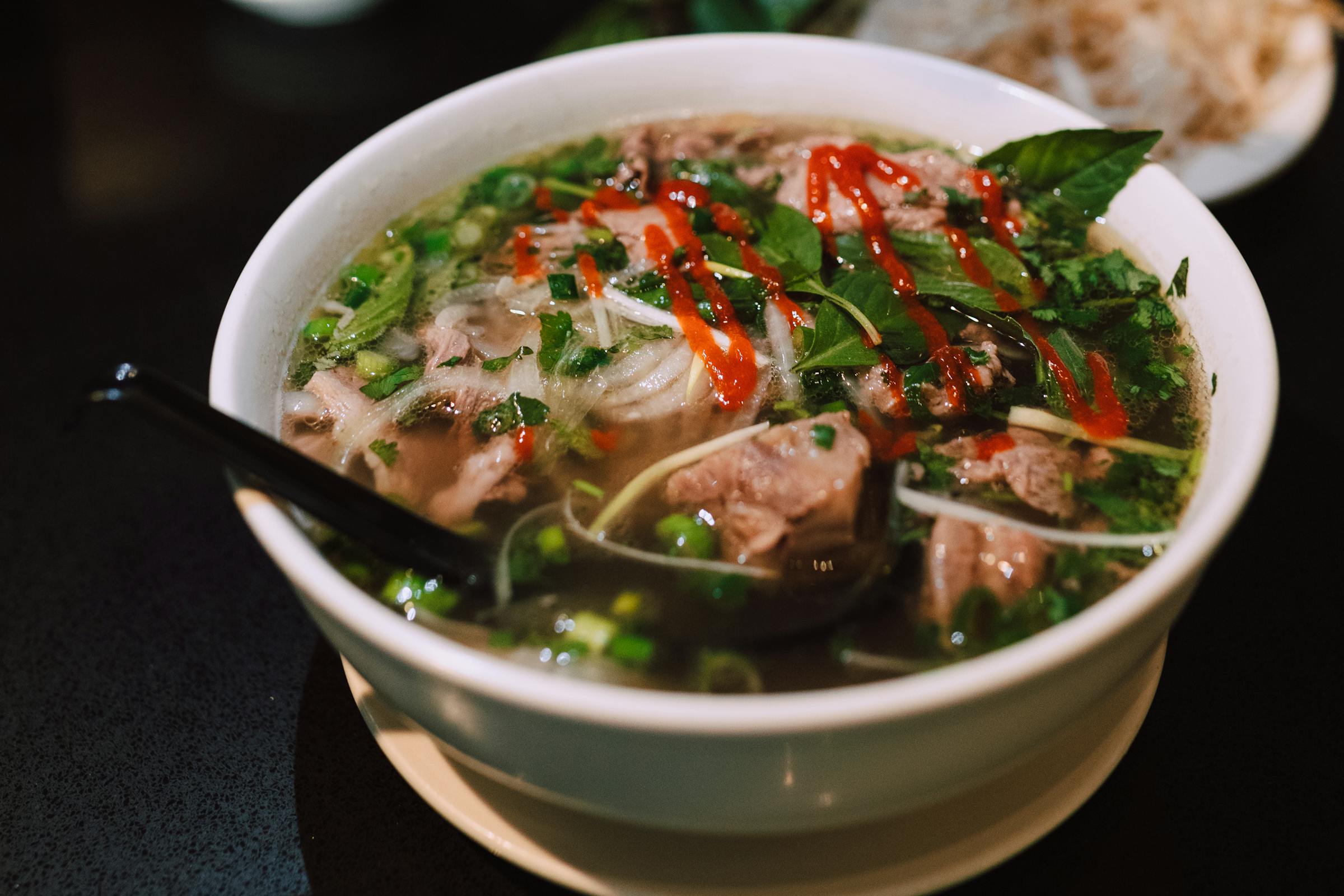 Dampfende Schale Phở mit Rindfleisch, frischen Kräutern und Chili